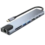 Na slici je prikazan moderan USB-C hub, koji je 8-u-1 multifunkcionalni uređaj. Ovaj hub ima elegantan dizajn u sivoj boji sa nekoliko različitih vrsta portova i konektora vidljivih na bočnoj strani. Na prvi pogled, uočljivi su dva USB 3.0 porta, HDMI port, Ethernet (RJ45) port, kao i slotovi za SD i microSD kartice. Takođe se vidi i USB-C port, najverovatnije za napajanje ili pass-through punjenje. Hub je opremljen sa kratkim, fiksnim USB-C kablom za povezivanje sa kompatibilnim uređajima poput laptopa, tableta ili pametnih telefona. Na vrhu se nalazi LED indikator koji verovatno pokazuje status napajanja ili aktivnosti hub-a. Uređaj je kompaktan i dizajniran da bude prenosiv, sa glatkim ivicama i tankim profilom koji olakšavaju transport i upotrebu u različitim radnim okruženjima.